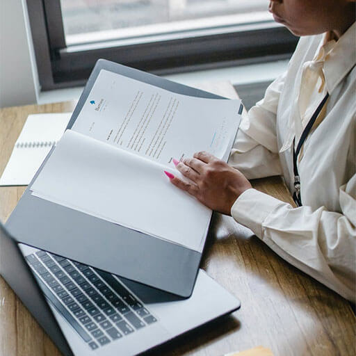 Woman reviewing documents in office with laptop