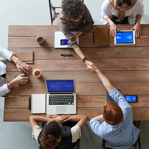 People shaking hands over boardroom table